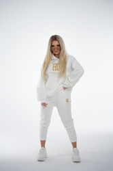 Brandenburg Couture DRES DAMSKI BG ROYAL SUEDE - biały - Komplet zamszowy BG ROYAL SUEDE w kolorze białym. Bluza kangurka z kapturem ozdobiona dużym haftowanym złotym logiem marki BG BRANDENBURG COUTURE. Spodnie posiadają gumkę w pasie. Na lewej kieszeni spodni wyhaftowane złote logo marki. Krój oversize. Ozdobne przeszycia na bluzie oraz spodniach.