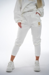 Brandenburg Couture DRES DAMSKI BG ROYAL SUEDE - biały - Komplet zamszowy BG ROYAL SUEDE w kolorze białym. Bluza kangurka z kapturem ozdobiona dużym haftowanym złotym logiem marki BG BRANDENBURG COUTURE. Spodnie posiadają gumkę w pasie. Na lewej kieszeni spodni wyhaftowane złote logo marki. Krój oversize. Ozdobne przeszycia na bluzie oraz spodniach.