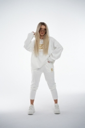 Brandenburg Couture DRES DAMSKI BG ROYAL SUEDE - biały - Komplet zamszowy BG ROYAL SUEDE w kolorze białym. Bluza kangurka z kapturem ozdobiona dużym haftowanym złotym logiem marki BG BRANDENBURG COUTURE. Spodnie posiadają gumkę w pasie. Na lewej kieszeni spodni wyhaftowane złote logo marki. Krój oversize. Ozdobne przeszycia na bluzie oraz spodniach.