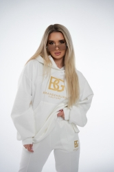 Brandenburg Couture DRES DAMSKI BG ROYAL SUEDE - biały - Komplet zamszowy BG ROYAL SUEDE w kolorze białym. Bluza kangurka z kapturem ozdobiona dużym haftowanym złotym logiem marki BG BRANDENBURG COUTURE. Spodnie posiadają gumkę w pasie. Na lewej kieszeni spodni wyhaftowane złote logo marki. Krój oversize. Ozdobne przeszycia na bluzie oraz spodniach.