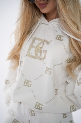 Brandenburg Couture DRES DAMSKI BG HOLO - biały - Komplet dresowy bawełniany (nieocieplany) w kolorze białym. Dres charakteryzuje się kontrastowym, przecieranym hologramem na całości w kolorze złotym. Bluza z kapturem oraz spodnie są ozdobione wyklejanymi, złotymi kryształkami w kształcie logo BG.  Komplet wykończony jest gumkami. Spodnie posiadają kieszenie oraz sznurek w pasie. Luźny krój.

Polska marka BG Brandenburg Couture.