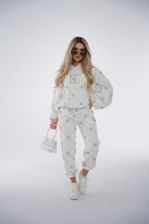 Brandenburg Couture DRES DAMSKI BG HOLO - biały - Komplet dresowy bawełniany (nieocieplany) w kolorze białym. Dres charakteryzuje się kontrastowym, przecieranym hologramem na całości w kolorze złotym. Bluza z kapturem oraz spodnie są ozdobione wyklejanymi, złotymi kryształkami w kształcie logo BG.  Komplet wykończony jest gumkami. Spodnie posiadają kieszenie oraz sznurek w pasie. Luźny krój.

Polska marka BG Brandenburg Couture.